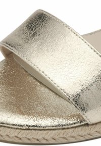 Metalické zlaté sandály na skluz s dvěma širokými popruhy, texturovaným povrchem a spletenou juteovou mezipodešví. Hladká vnitřní podšívka a plochá podešev.