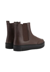 Botas de tobillo de cuero marrón con paneles laterales elásticos, suela de goma negra texturizada y un acabado suave. Presentan una punta redondeada y un tacón bajo.