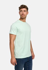 Light mint green cotton t-shirt with a crew neck, short sleeves, and a relaxed fit, paired with blue denim jeans.