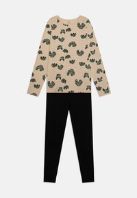 Beige Langarmshirt mit grünen und schwarzen Mustern, kombiniert mit schwarzen Leggings. Weicher Stoff, lockere Passform, auffälliges Printdesign.