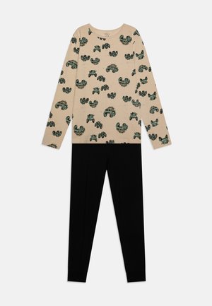 Beige Langarmshirt mit grünen und schwarzen Mustern, kombiniert mit schwarzen Leggings. Weicher Stoff, lockere Passform, auffälliges Printdesign.