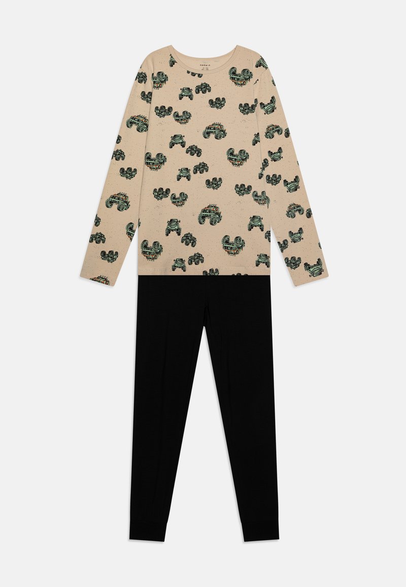 Beige Langarmshirt mit grünen und schwarzen Mustern, kombiniert mit schwarzen Leggings. Weicher Stoff, lockere Passform, auffälliges Printdesign.