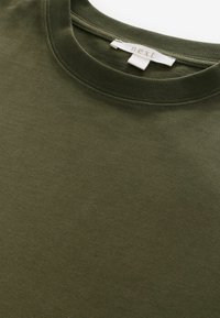 Oliven grøn bomulds T-shirt med rund halsudskæring og blød tekstur. Indeholder et mærke med "next" syet i kraven.