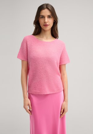 Korte mouw, loszittende roze gebreide trui met een ronde hals en een zachte textuur, gedragen over een lange roze satijnen rok.