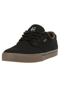Black canvas sneaker with a rubber sole, brown accents, and round laces. Features a logo on the side and a padded collar.