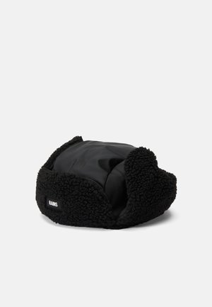Black faux fur hat with a quilted black lining. Features a rounded shape with ear flaps, a branded label on the side, and a soft texture.