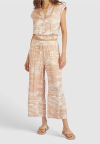 Conjunto de dos piezas en melocotón claro con patrones abstractos en blanco. Top corto de manga corta y pantalones de pierna ancha con cintura elástica.