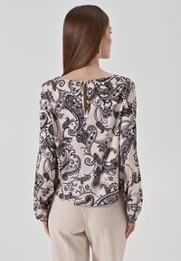 Blusa nera a motivo paisley in morbido tessuto rosa, presenta maniche lunghe, scollo rotondo e una apertura a occhio di chiave sul retro.