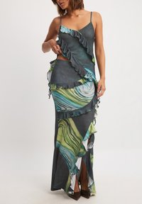 Maxi dress with spaghetti straps, featuring a marbled pattern in green, blue, and gray, layered ruffles, and a side cutout.