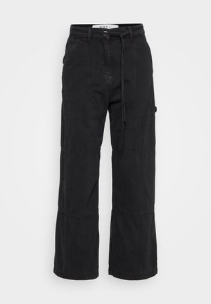 Schwarze weit geschnittene Baumwollhosen mit strukturierter Oberfläche. Verfügt über eine Taillengürtel und Akzente an den Kniefalten für zusätzliche Details.