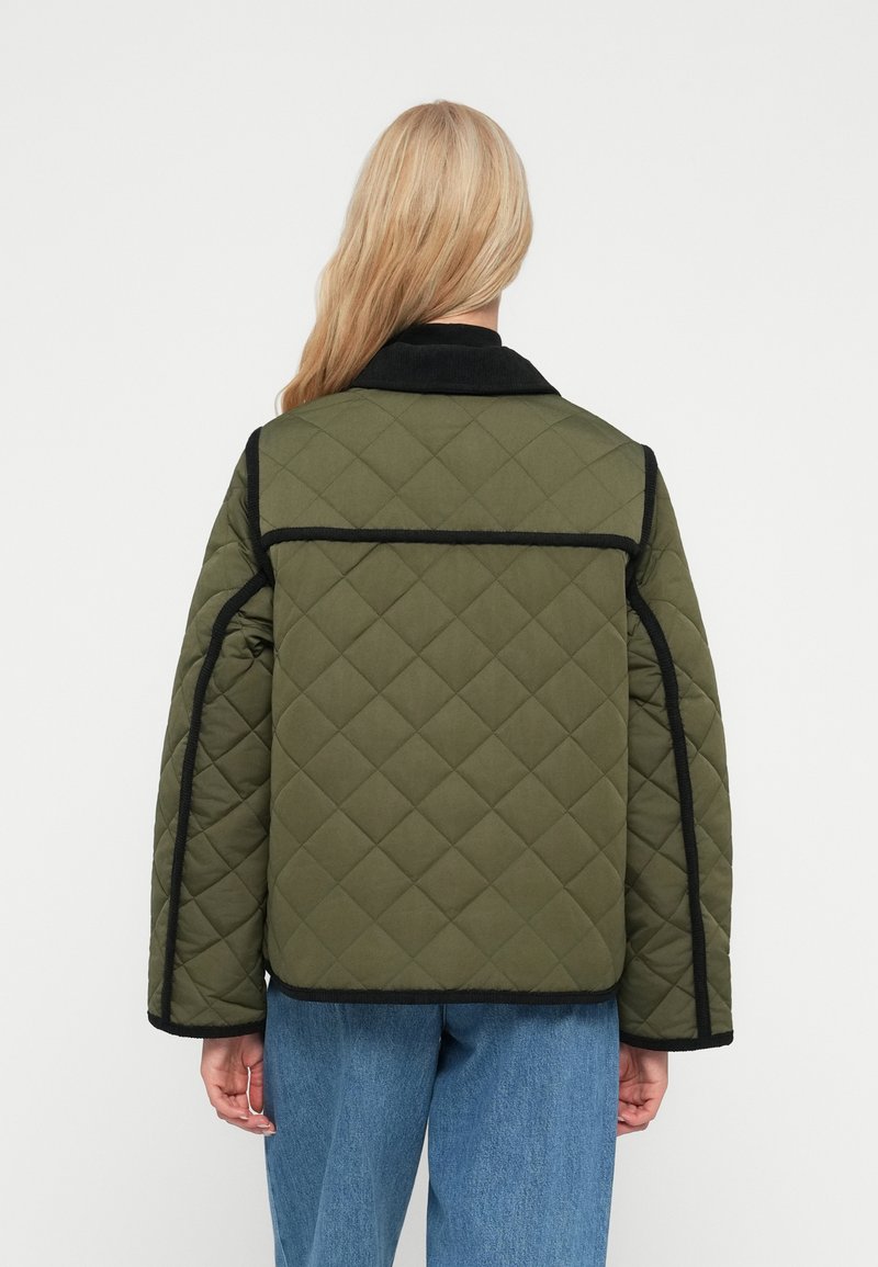 Olivgrüne gesteppte Jacke mit schwarzem Saum, die über einen Kragen und eine oversized Passform verfügt. Die Rückansicht zeigt ein Rautenmuster und lockere Ärmel.