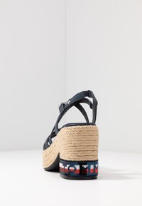 Námořnické sandály na platformě s popruhy, které mají espadrilový jutu podpatek se vzorovaným textilním akcentem na spodní části. Zavřená zadní část s nastavitelným popruhem.