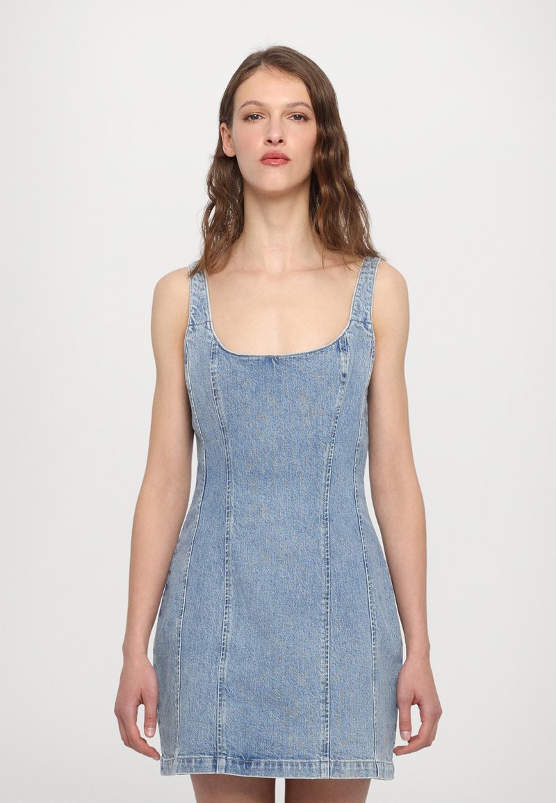 Denim mini kleit ruudukujulise kaelusega, paksude rihmadega ja lähedase siluetiga. Helesinine värv, avatud õmblused ja pehme tekstuur.