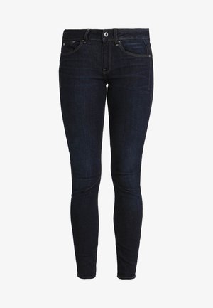 Ozke kavbojke v temno modrem jeansu, ki imajo klasičen dizajn s petimi žepi, zankami za pas in gumbnim zapiranjem. Gladka tekstura, brez vidnih vzorcev.