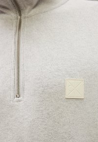 Ανοιχτό γκρι ριγωτό πουλόβερ με σχέδιο μισής ζώνης, με υφή υφάσματος και τετράγωνο δερμάτινο ένθετο στο στήθος.