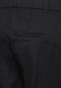 Svarta byxor med en slät yta, med en platt bakficka och ett stretchigt midjeband för komfort. Enkel, klassisk design.