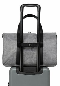 Sac de sport en tissu gris fixé sur le dessus d'une valise rigide grise ; dispose de poignées de transport noires et d'une poignée télescopique.