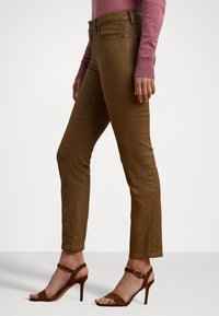 Bruna jeans i stretchig denim, med medelhög midja och smala ben, parat med bruna högklackade sandaler.