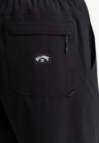 Pantalones cortos negros de tejido texturizado, con un bolsillo trasero con etiqueta, cinturilla elástica y detalle de cordón.
