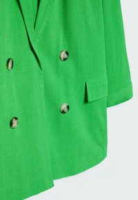 Groen dubbelgeknoopt blazer van een gestructureerde stof, met grote ronde knopen en een enkele borstzak. Korte, opgestroopte mouwen.