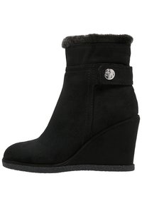 Bottines à talon noir en suède avec une doublure en fausse fourrure douce. Elles présentent un bouton décoratif sur le côté et une semelle texturée.