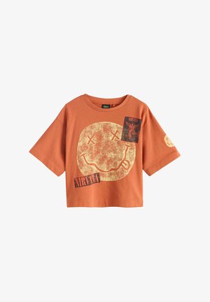 Rustorange kortærmet crop top med slidt gul smiley, krydsede øjne og "Nirvana" tekst og grafiktryk på front og ærme.