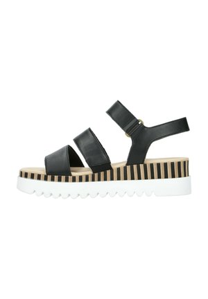 Sort platformsandal med tre remme og en stribet mellemsål oven på en hvid takkekant, sidevisning på hvid baggrund.