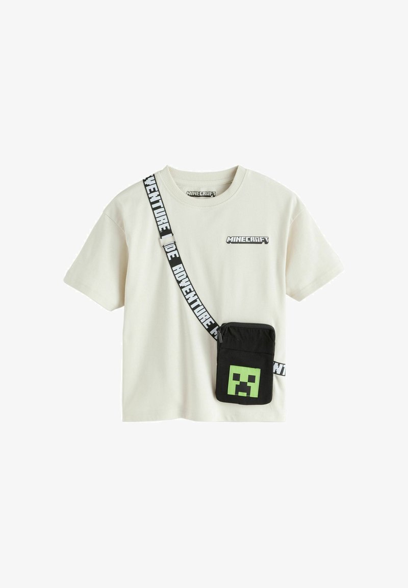 T-shirt Minecraft blanc avec pochette noire en bandoulière ornée d'un visage pixellisé vert et du texte "AVENTURE" sur la sangle.