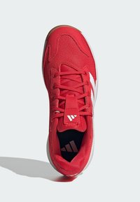 Chaussure de sport rouge avec tige en mesh, accents de marque blancs, lacets texturés et semelle en caoutchouc. Comprend un collier et une languette rembourrés.