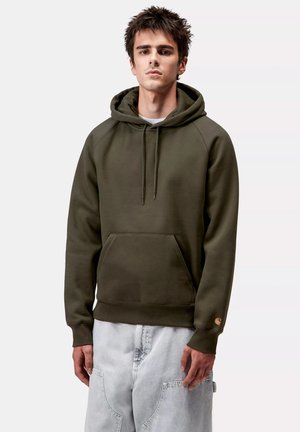 Felpa in cotone verde oliva con tasca a marsupio, cappuccio con coulisse, maniche raglan e un patch con logo sulla manica sinistra.