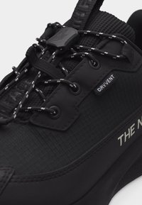 Baskets imperméables noires avec lacets réfléchissants, fermeture à bascule, languette rembourrée et étiquette en tissu « DRYVENT » sur le côté.