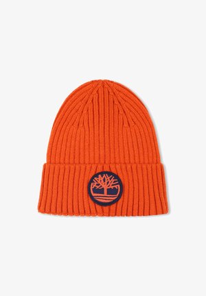 Een oranje gebreide beanie met een ribbeltextuur en een omgeslagen rand. Bevat een ronde marineblauwe patch met een boomlogo aan de voorkant.