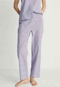 Lichtpaarse pyjama set met verticale witte strepen; het topje heeft knopen en een ontspannen pasvorm; de broek heeft een rechte pijpstijl en zijzakken.