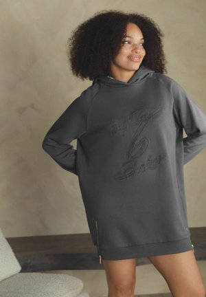 Tmavě šedé oversized mikinové šaty s texturovaným vzorem loga. Mají kapuci, boční zipy a žebrované manžety pro volný střih.