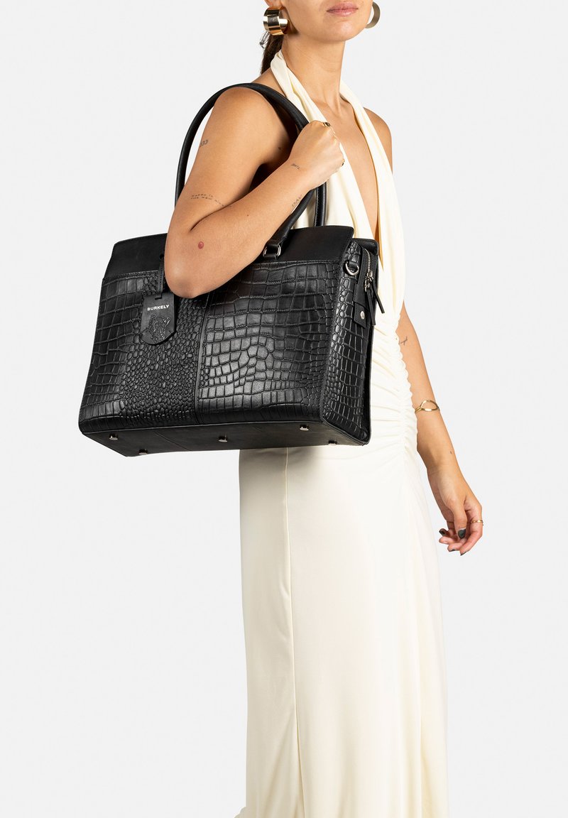 Borsa a tracolla in pelle nera con texture coccodrillo, hardware in acciaio inox, doppio manico, dotata di un'etichetta removibile e quattro piedi metallici alla base.