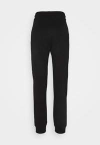 Pantalon de survêtement noir fuselé avec taille élastique et chevilles resserrées, vu de dos sur fond blanc.