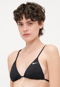 Svart trianglig bikiniöverdela med tunna justerbara remmar, med en rynkad mittsöm och en liten vit Nike-logotyp på vänster sida.