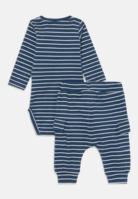 Blaue und weiße gestreifte langärmelige Bodysuit, kombiniert mit passenden Hosen, die über eine gerippte Textur und einen Druckknopfverschluss für ein einfaches Ankleiden verfügen.