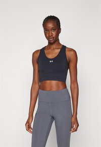 Sujetador deportivo en azul marino oscuro con escote redondeado y diseño de espalda nadadora. Combinado con leggings gris de cintura alta. Ambos están hechos de un tejido elástico y suave.