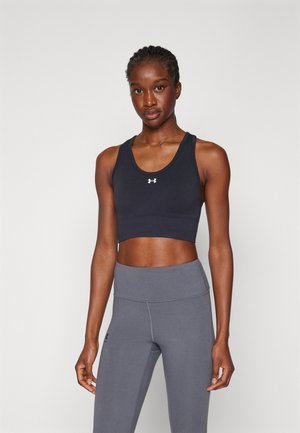Dark navy sports bra with a scoop neckline and racerback design. Paired with high-waisted gray leggings. Both are made from stretchy, smooth fabric.