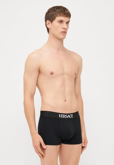 Sorte bomull boxer briefs med en bred elastisk linning merket "VERSACE" i hvitt. Materialet ser glatt ut, med en tettsittende design.