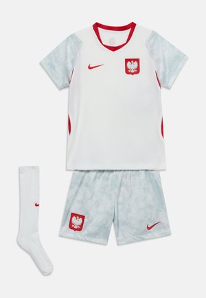 Wit en lichtgrijs Pools voetbaltenue met rode accenten, inclusief shirt, korte broek en één sok, voorzien van Nike-logo's en een adelaarsembleem.