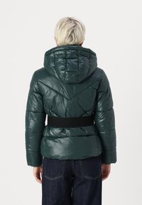Padded green jacket with a quilted design and hood, featuring a black fabric belt at the waist and a glossy finish.
