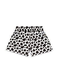 Shorts à taille élastique imprimé vache noir et blanc, posés à plat, sans détails en arrière-plan.