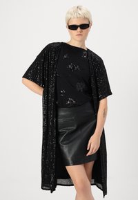 Fekete flitteres kimono dzseki fekete, textúrált virágmintás felsõvel; bőr szoknyával párosítva. A modellen fekete napszemüveg van.