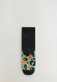 Svart ankelsocka med orange och teal leopardmönster på den nedre halvan, med en mjuk textur och rund tå.