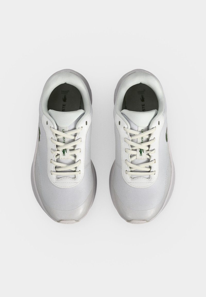 Paar weiße Lacoste Sneaker mit Schnürsenkeln, von oben auf einem hellgrauen Hintergrund gesehen.