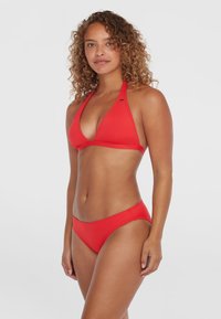 Červený bikiny s halter topom a nastaviteľnými viazaniami. Hladký, elastický materiál; spodná časť má dizajn s miernym zvýšením.