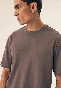 T-shirt z krótkim rękawem, okrągłym dekoltem w stonowanym odcieniu mauve, wykonany z miękkiej mieszanki bawełny z gładką teksturą i minimalnymi detalami szwów.