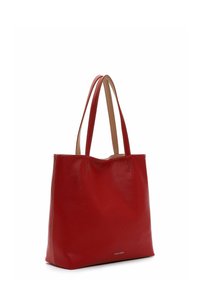 Sac fourre-tout en cuir rouge avec une texture lisse, doté de poignées beiges doubles et de détails de couture subtils, ainsi qu'un logo en bas à l'avant.
